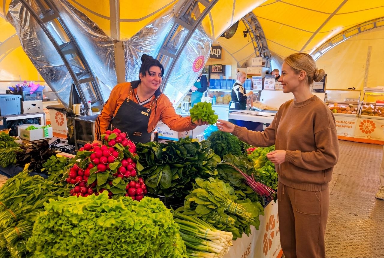 Продавец и покупатель у прилавка со свежей зеленью